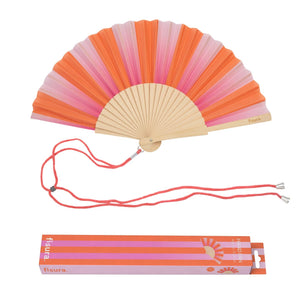 Open handheld fan with wooden ribs and a pink and orange striped design. The fan is attached to an orange lanyard to wear around your neck. The packaging for the box sits underneath the fan. 