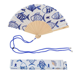 Handheld fan with wooden ribs and a blue fish design on a white background. The fan is attached to a blue lanyard to wear around your neck. The packaging box for the fan sits underneath it. 