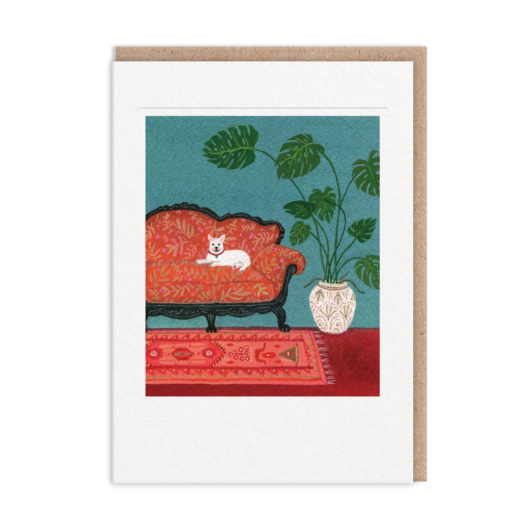 Greeting card showing artwork of a living room scene with a red sofa, white dog, and potted plant. The artwork is surrounded by a white border. 