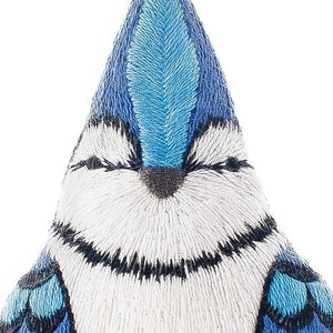 Close-up of an embroidered bluejay plush doll against a plain white background, showing blue, white, and black stitched details.
