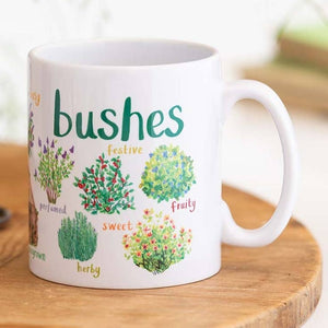 A white mug with colourful illustrations of different types of bushes. The text 'Bushes' is printed over the illustrations along with text labelling each image. The mug sits on a wooden surface. 