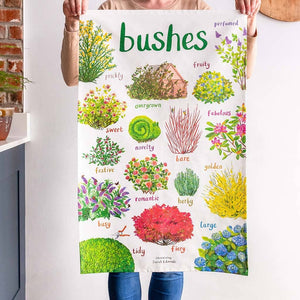 A person is holding up a white cotton tea towel showing colourful illustrations of bushes with text printed underneath. The heading 'bushes' is printed at the top. 