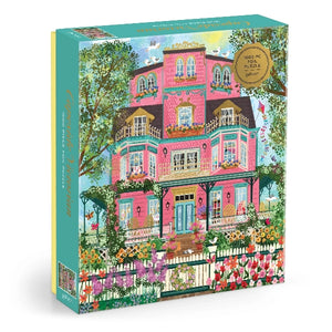 Jigsaw puzzle box with a colorful illustration of a pink house and flower filled garden on a white background.