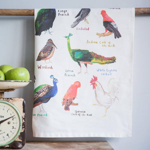 Tea towel with a humorous bird-themed print featuring different types of cock birds, hanging on a wooden rail. 