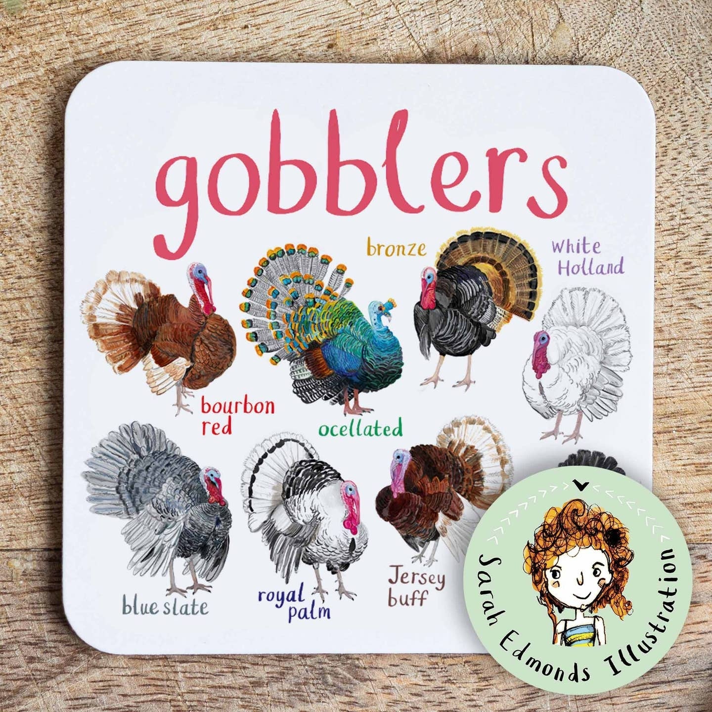 Coaster featuring illustrations of turkeys on a white background. Each turkey is labelled, while the text 'Gobblers' is printed on the top. The coaster sits on a wooden surface.