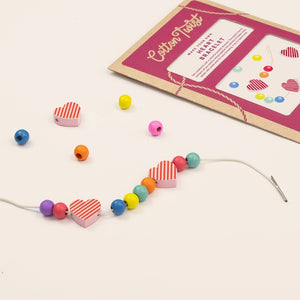 Colorful beaded bracelet with heart-shaped beads with packaging on a white background.