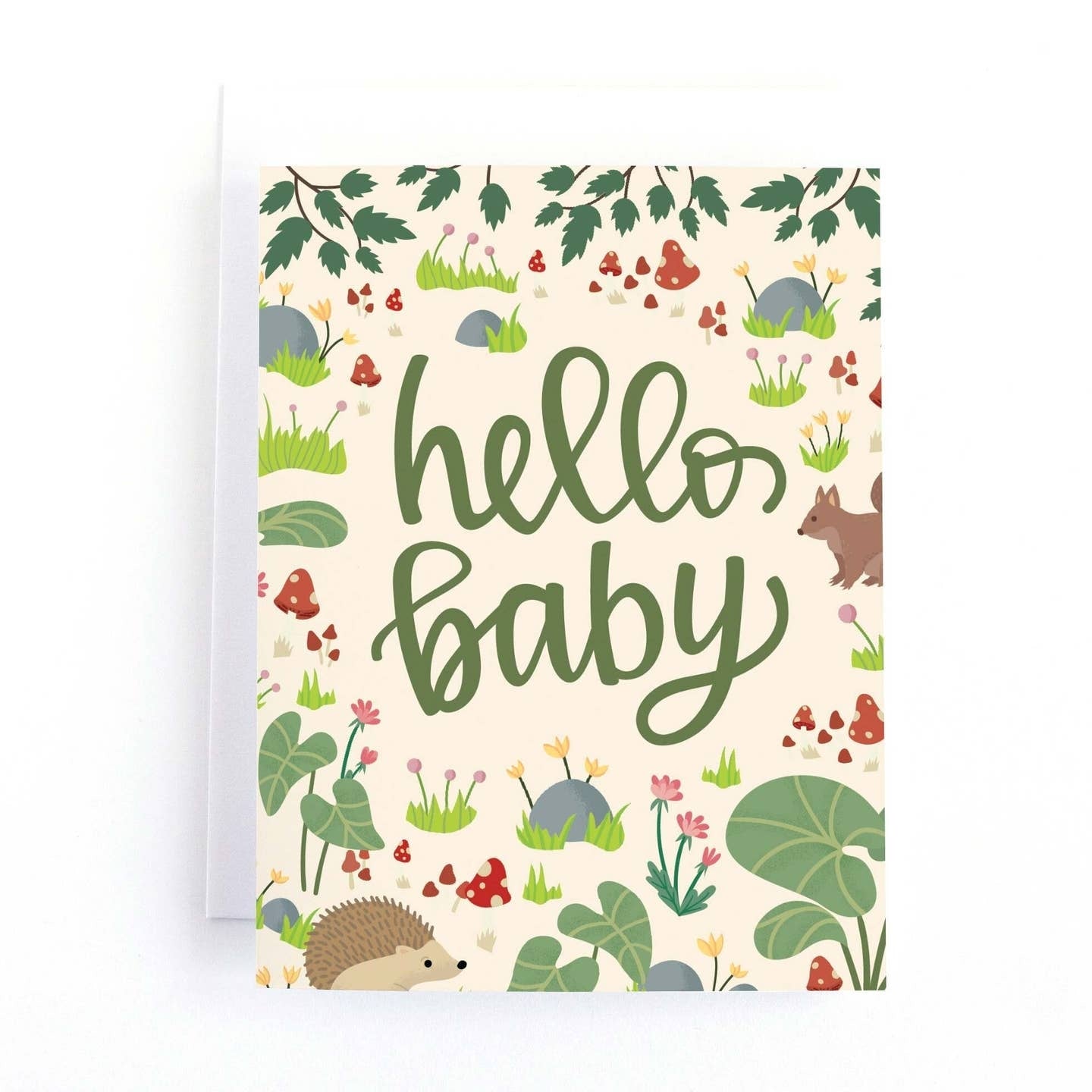 Greeting card featuring a woodland themed illustration of a hedgehog, a squirrel, mushrooms and clumps of grass with flowers on a cream coloured background. The text 'Hello baby' is printed in the centre of the card.  