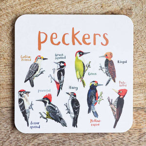 Coaster featuring illustrations of birds on a white background. Each bird is labelled, while the text 'Peckers' is printed on the top. The coaster sits on a wooden surface.