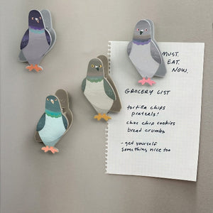 Image of four pigeon-themed magnetic bag clips stuck to a fridge, along with piece of paper with groceries listed. 