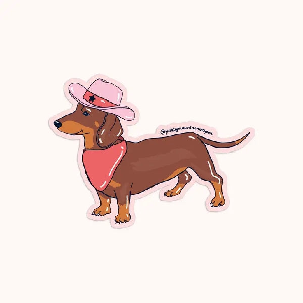 pink die-cut sticker of a smiling weener dog wearing a pink cowboy hat and scarf